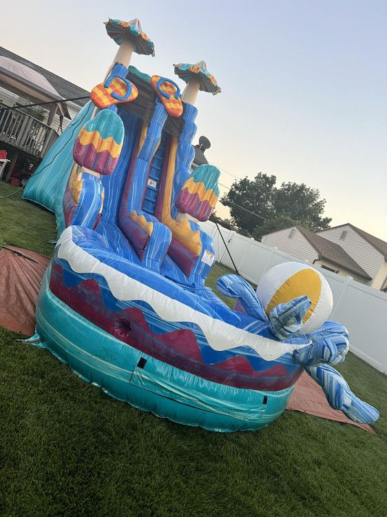 Bright inflatable water slide with splash pool set up on a sunny lawn